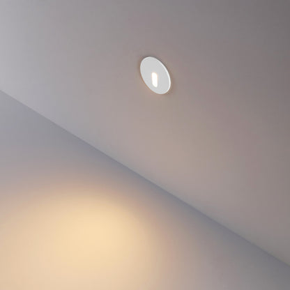 Rond wit kapje gemonteerd in de wand, smalle lichtbundel naar beneden