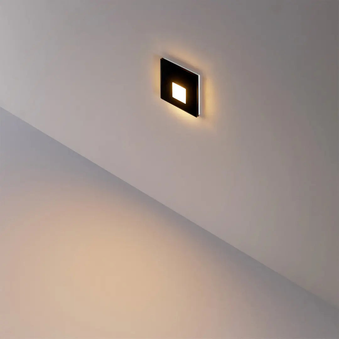 Vierkant zwart glaskapje gemonteerd in de wand naast de trap