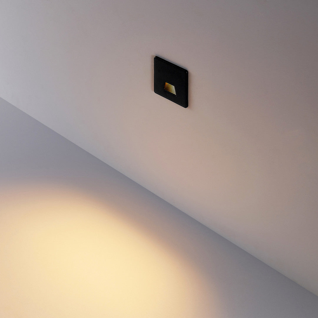 Vierkant zwart kapje gemonteerd in de wand, brede lichtbundel over de trede